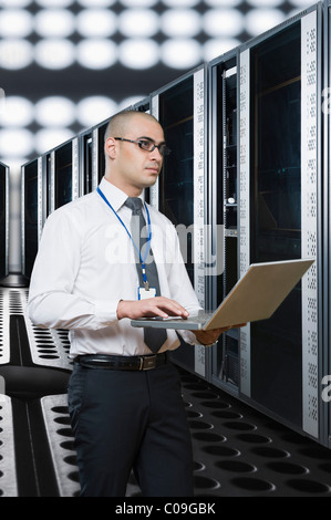 Technicien travaillant sur un ordinateur portable dans une salle de serveur Banque D'Images