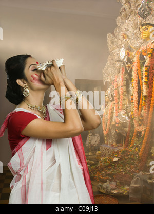 Woman blowing conque à Durga puja Banque D'Images