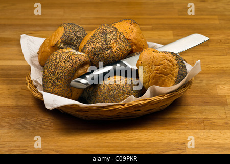 Des petits pains frais et le couteau dans le panier sur la table en bois Banque D'Images