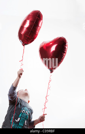 Jeune garçon tenant un ballon en forme de coeur Banque D'Images