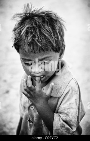 Les jeunes Indiens de caste inférieure pauvre bébé garçon à la recherche de la rue vers le bas. L'Andhra Pradesh, Inde. Noir et blanc. Banque D'Images