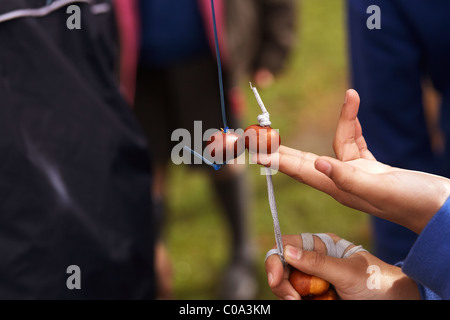 Des enfants qui jouent un jeu de conkers dans l'aire de jeux à l'école vêtu de l'uniforme bleu Banque D'Images