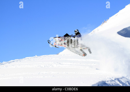 Motoneige sur montagne en hiver haut saut à partir de la colline raide sur de grandes corniches dangereuses. Banque D'Images