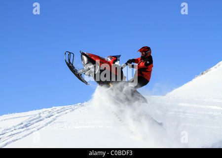 Motoneige sur montagne en hiver sauter de colline raide sur de grandes corniches dangereuses. Banque D'Images