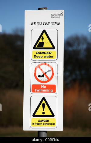 Un signe pour conseiller les gens à être sage de l'eau, à côté d'un lac à l'intérieur de Herrington Country Park, Sunderland, NE Englandwarning Banque D'Images