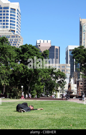 HOMME SANS-ABRI ENDORMI SUR LA PELOUSE À HYDE PARK, SYDNEY, NOUVELLE-GALLES DU SUD, AUSTRALIE. Banque D'Images