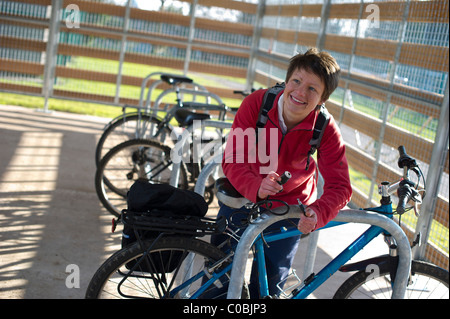 Une élève cycliste bloque son vélo dans un parc de vélo sur le campus à l'Université d'Exeter Banque D'Images