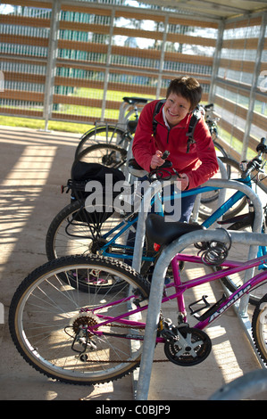 Un cycliste féminin bloque son vélo dans un parc de vélo à l'Université d'Exeter, Devon Banque D'Images