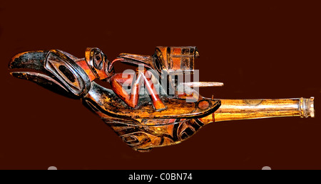 Hochet de corbeau en bois sculpté et peint de la côte nord-ouest du Pacifique, orné d'une figure humaine couchée et de motifs artistiques. Banque D'Images