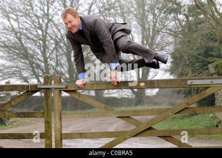 Adam Henson agriculteur Cotswold et présentatrice TV saute sa ferme portant un tailleur Savile Row bespoke Banque D'Images