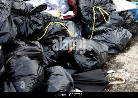 Une pile de sacs poubelle noirs contenant des déchets et ordures déversées sur un site public prêt pour enlèvement par le Conseil. Banque D'Images