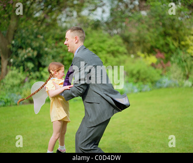 Père lifting daughter wearing fairy wings Banque D'Images