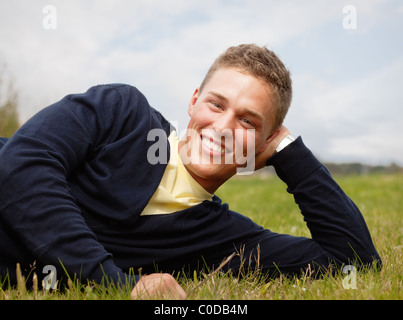 Jeune homme blond allongé sur l'herbe Banque D'Images