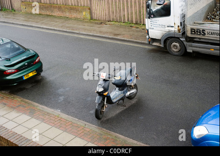 Cycle de moteur propriétaire irresponsable en prenant une place de stationnement de voiture tout en camion stationné sur une rue résidentielle double yellow lines Banque D'Images