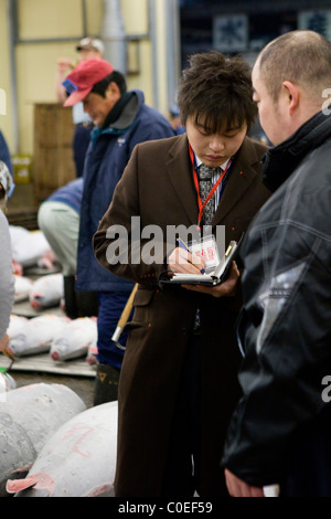 L'homme en prenant des offres lors d'une vente aux enchères des thons congelés au marché aux poissons de Tsukiji à Tokyo Banque D'Images