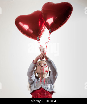 Happy girl holding a heart shaped balloon Banque D'Images