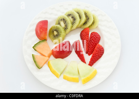 Cinq morceaux de salade de fruits frais haché sur une plaque blanche pour illustrer cinq par jour. Banque D'Images