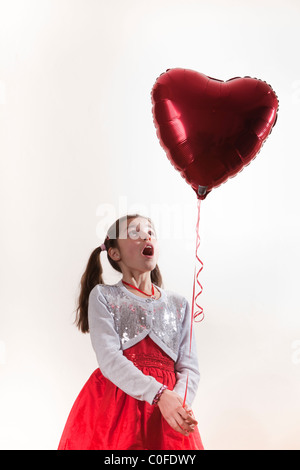 Happy girl holding a heart shaped balloon Banque D'Images