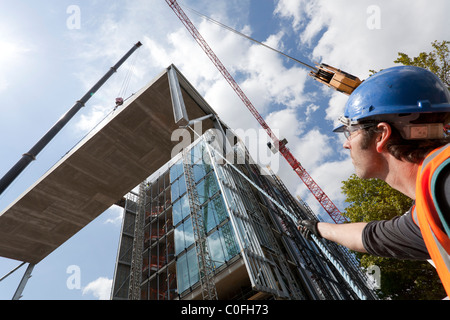 L'opérateur maintient des cordes pour levage grue guide sur chantier de construction. Banque D'Images