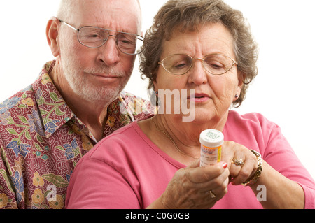 Senior Couple lit une bouteille de prescription en collaboration avec regard sur leurs visages tous sur un fond blanc. Banque D'Images