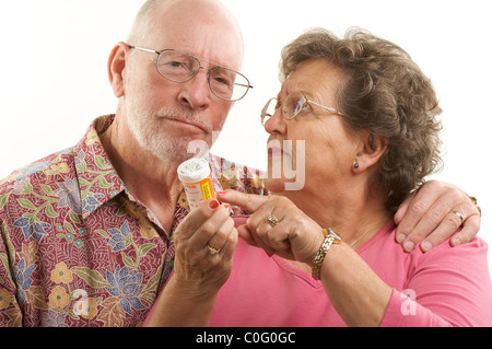 Senior Couple lit une bouteille de prescription en collaboration avec regard sur leurs visages tous sur un fond blanc. Banque D'Images