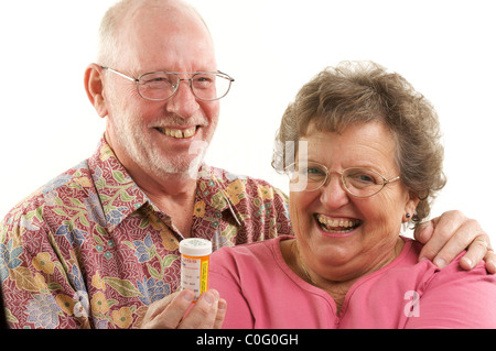 Senior Couple lit une bouteille de prescription de rire ensemble sur un fond blanc. Banque D'Images