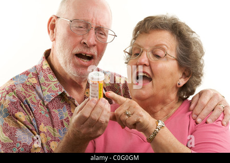 Senior Couple lit une bouteille de prescription ensemble sur un fond blanc. Banque D'Images