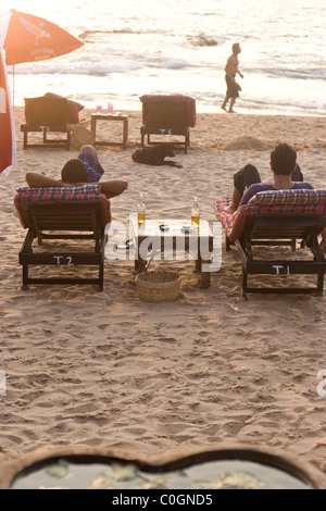 Les vacanciers appréciant une bière sur la plage. Banque D'Images