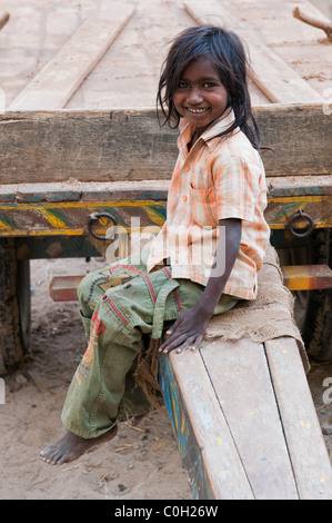 Smiling happy jeunes pauvres caste inférieure Indian street girl playing sur charrette. L'Andhra Pradesh, Inde Banque D'Images