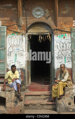 Les hommes assis sur les marches d'un bâtiment dans les petites rues de Kumartuli, Kolkata (Calcutta), West Bengal, India Banque D'Images