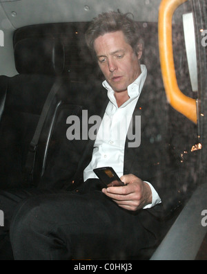 Hugh Grant vérifie son téléphone portable attentivement, pendant qu'il part le Dorchester Hotel, où son ex petite amie Jemima Khan a également dépensé Banque D'Images