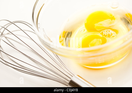 Oeufs dans un bol en verre sur un fond blanc réfléchissant. Banque D'Images