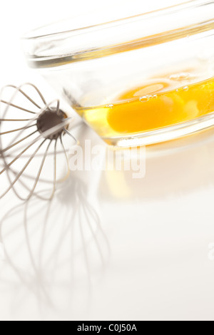 Oeufs dans un bol en verre sur un fond blanc réfléchissant. Banque D'Images