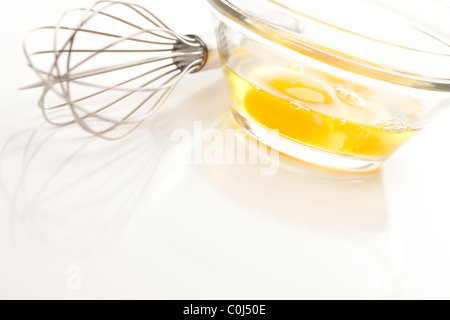 Oeufs dans un bol en verre sur un fond blanc réfléchissant. Banque D'Images