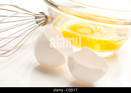 Oeufs dans un bol en verre sur un fond blanc réfléchissant. Banque D'Images