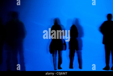 Silhouettes de personnes contre un fond bleu mystérieux Banque D'Images