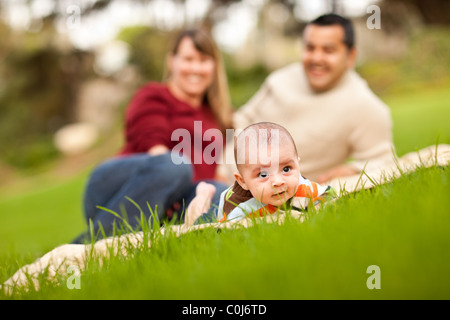 Heureux de ramper Baby Boy and Mixed Race Parents jouant dans le parc. Banque D'Images