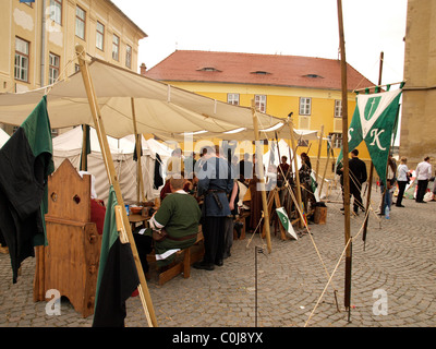 Des gens habillés en tant que Chevaliers et manger autour d'une table en bois Festival médiéval, Transylvanie, Sibiu, Roumanie. Banque D'Images