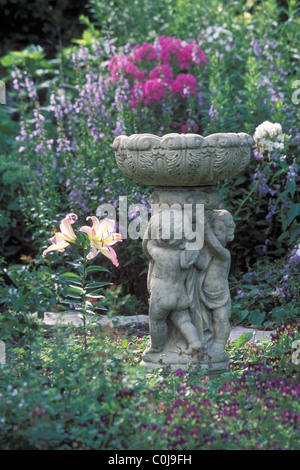 BIRDBATH CONCRET À MINNEAPOLIS dans le jardin de banlieue entourée de plantes vivaces. L'été. Banque D'Images