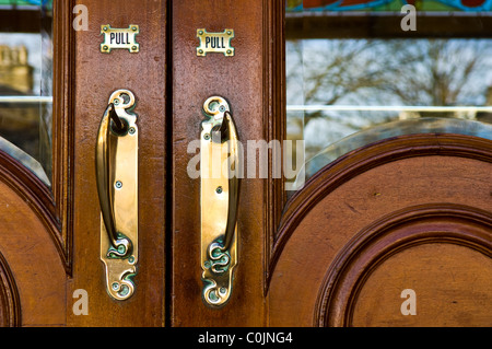 Poignées de porte en laiton massif montés sur les portes en chêne foncé à l'entrée de opéra de Buxton à Buxton, Derbyshire, Angleterre Banque D'Images