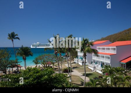 Bateau de croisière dans les Caraïbes voiles au-delà d'un complexe de l'hôtel au toit rouge sur la plage avec des palmiers Banque D'Images