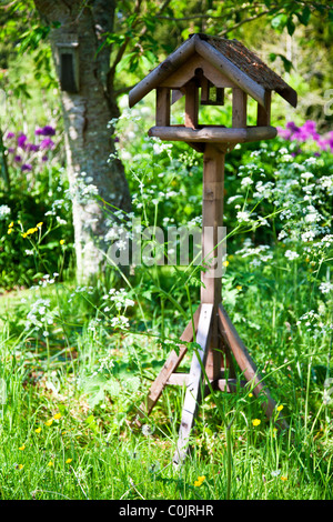 Une jolie table en bois rustique, d'oiseaux ou des parterres ou des lits dans un jardin de campagne anglaise en été Banque D'Images