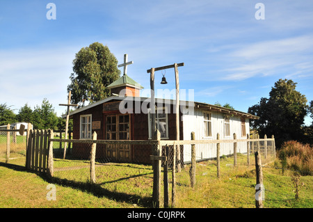 Ciel bleu, herbe verte vue sur le petit rural chapelle en bois de Notre Dame de Lourdes, près de chacao, Ile de Chiloé, Chili Banque D'Images