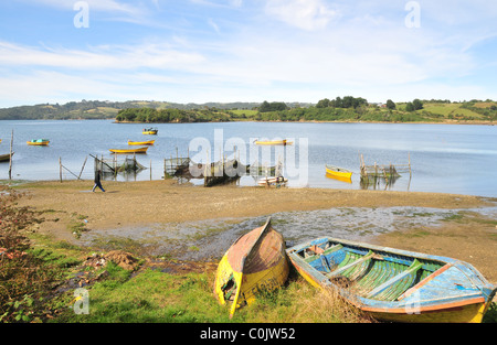 Sunny Beach vue sur la plage de la rangée du haut et bateaux de pêche d'algues des fascines au bord de l'eau, Golfe Quetalmahue, Ile de Chiloé, Chili Banque D'Images