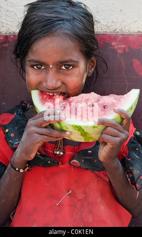 Heureux jeunes pauvres caste inférieure Indian street girl eating une tranche de pastèque. L'Andhra Pradesh, Inde Banque D'Images