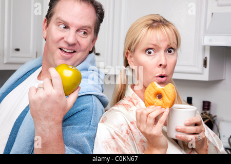 Couple in Kitchen Eating Donut et de café ou de fruits sains. Banque D'Images