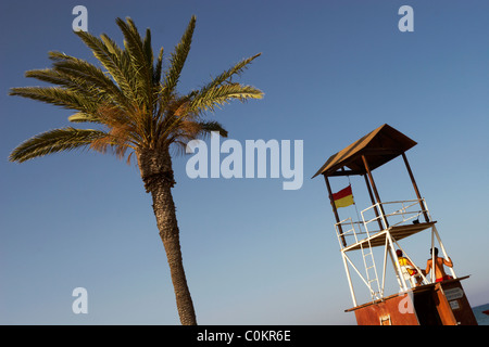 Watch sauveteurs sur une tour près d'un palmier sur la plage Mackenzie, Larnaca, Chypre. Banque D'Images