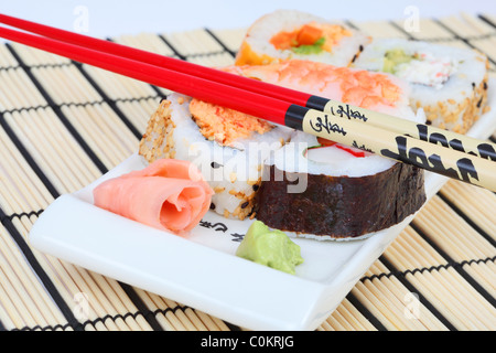 Sushi mixte sur une plaque avec wasabl, gingembre et baguettes Banque D'Images