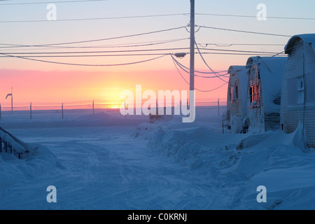 Premier lever du soleil en 84 jours à Barrow, AK dans le cercle arctique à la recherche de type quonset passé certains sur l'aérodrome. Banque D'Images