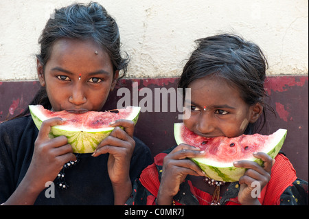 Heureux les pauvres jeunes filles de la rue indienne des castes inférieures (soeurs) de manger une tranche de pastèque. L'Andhra Pradesh, Inde Banque D'Images